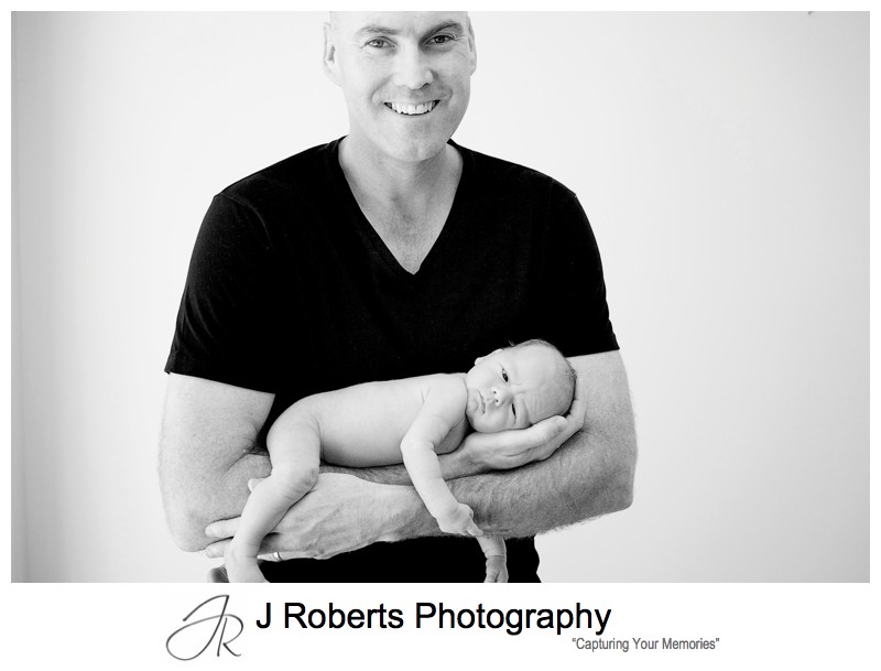 B&W portrait of a father with a newborn baby boy in his arms - newborn baby portrait photography sydney